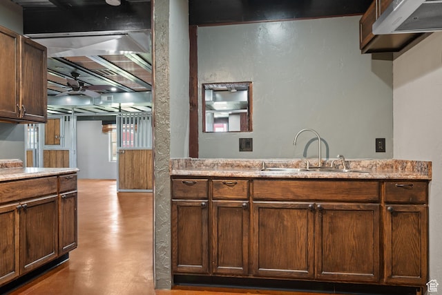 kitchen with a ceiling fan, concrete floors, light countertops, and a sink