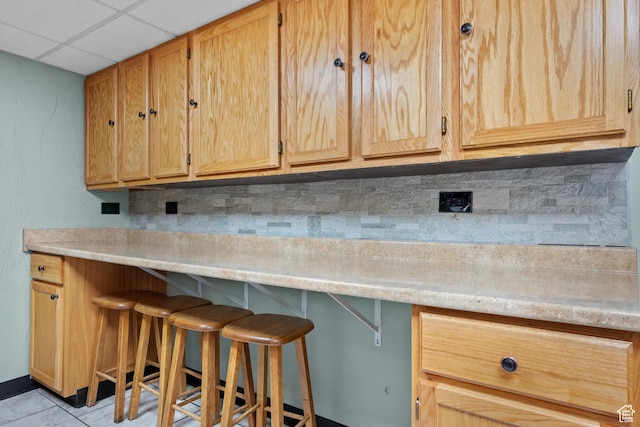 kitchen with a kitchen breakfast bar, a drop ceiling, and light countertops