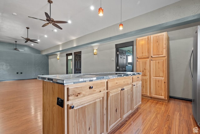 kitchen with lofted ceiling, tile counters, light brown cabinets, and light wood finished floors