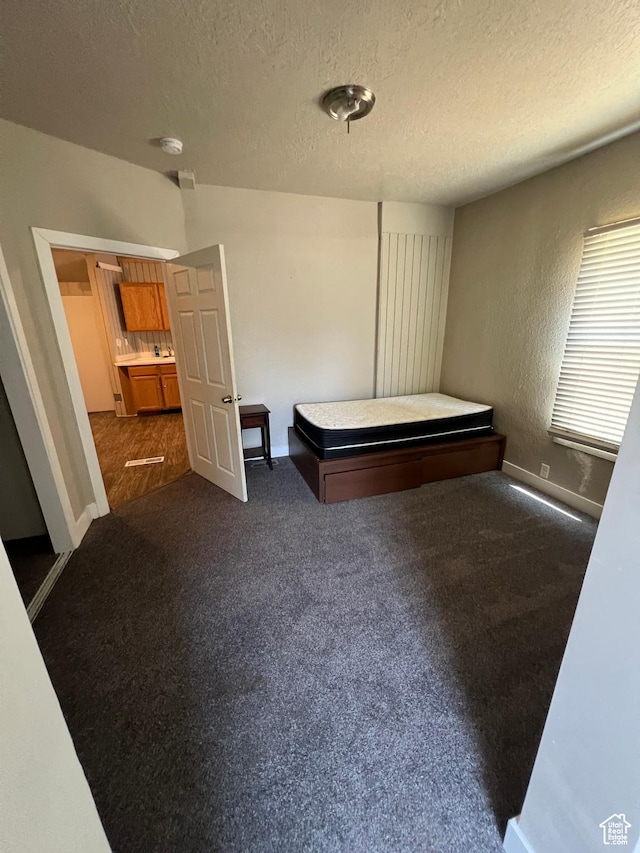 667 E 26th St S, Ogden, UT 84401 - unfurnished bedroom with a textured ceiling, dark colored carpet, and baseboards