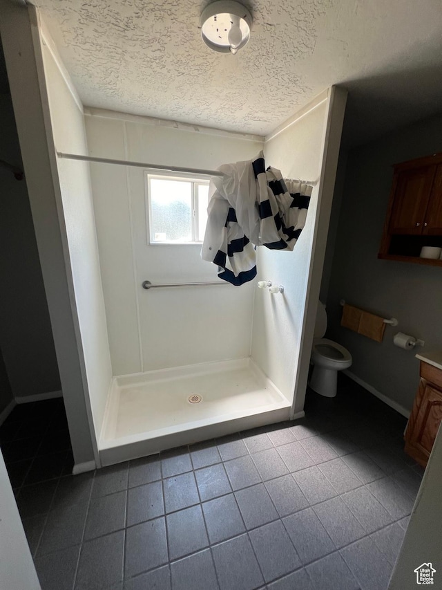 667 E 26th St S, Ogden, UT 84401 - bathroom featuring toilet, a stall shower, a textured ceiling, and tile patterned floors