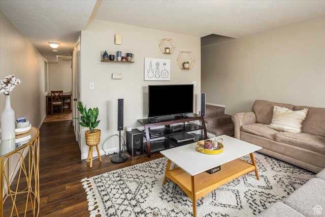 living area featuring a textured ceiling, hardwood / wood-style flooring, and baseboards
