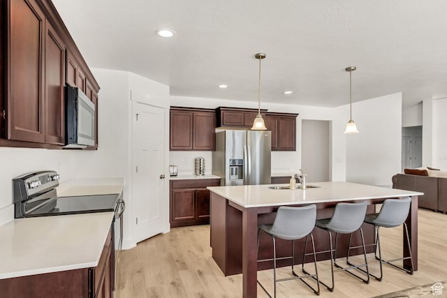 188 E Bruin Dr, Eagle Mountain, UT 84005 - kitchen featuring appliances with stainless steel finishes, light wood finished floors, light countertops, a breakfast bar area, and pendant lighting