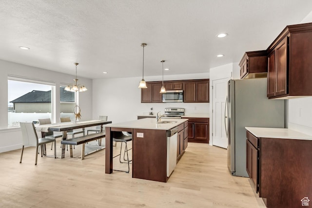 188 E Bruin Dr, Eagle Mountain, UT 84005 - kitchen with stainless steel appliances, light wood-style flooring, a center island with sink, recessed lighting, and a chandelier
