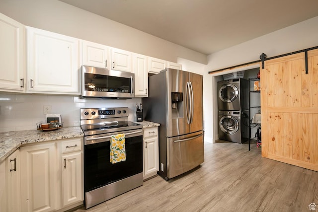 4947 W Calton Ln, South Jordan, UT 84009 - kitchen featuring stacked washer / drying machine, a barn door, tasteful backsplash, white cabinetry, and appliances with stainless steel finishes