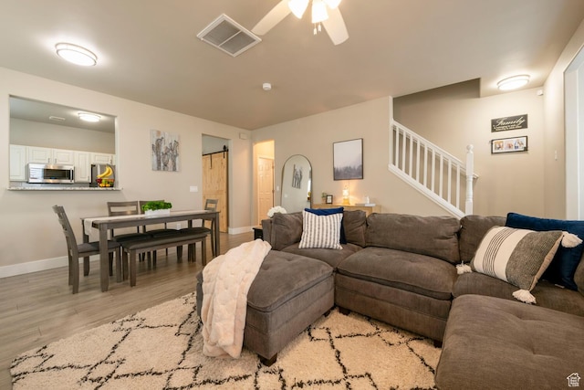 4947 W Calton Ln, South Jordan, UT 84009 - living room with light wood finished floors, a ceiling fan, visible vents, stairs, and baseboards