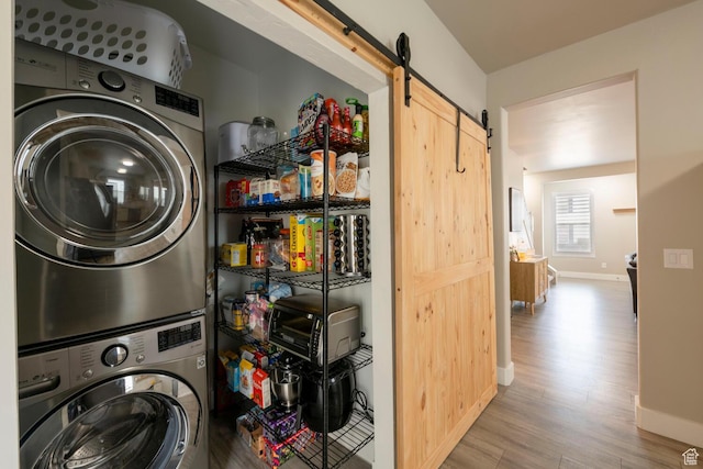 4947 W Calton Ln, South Jordan, UT 84009 - washroom with stacked washer and clothes dryer, a barn door, baseboards, wood finished floors, and laundry area