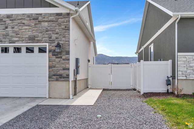 3498 N Delta St, Eagle Mountain, UT 84005 - view of property exterior featuring stone siding, a mountain view, stucco siding, and a gate