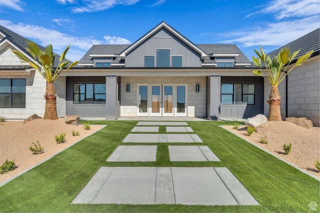 back of property featuring board and batten siding, a yard, and french doors