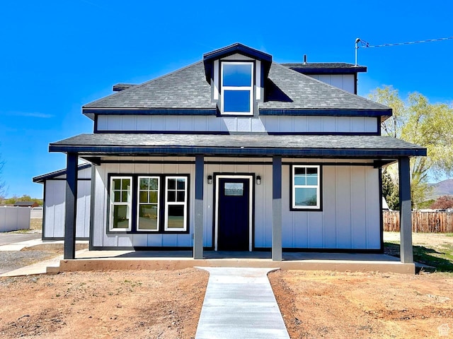 bungalow-style house featuring fence, covered porch, and a shingled roof