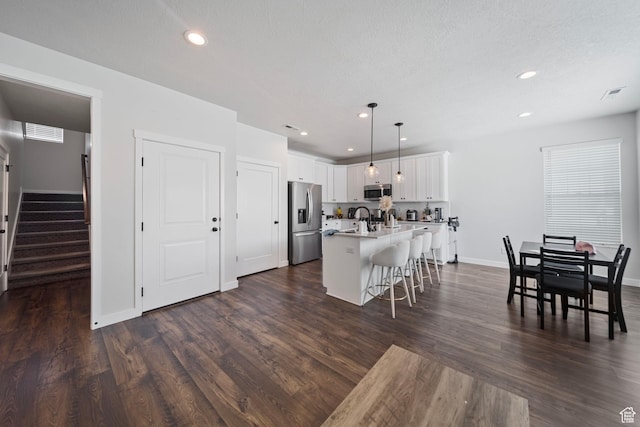 11412 S Regalstone Dr, South Jordan, UT 84009 - kitchen with a sink, a kitchen island with sink, visible vents, a breakfast bar area, and appliances with stainless steel finishes