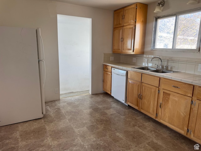 kitchen featuring a sink, tile counters, brown cabinetry, backsplash, and white appliances