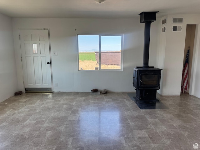 unfurnished living room with a wood stove and visible vents