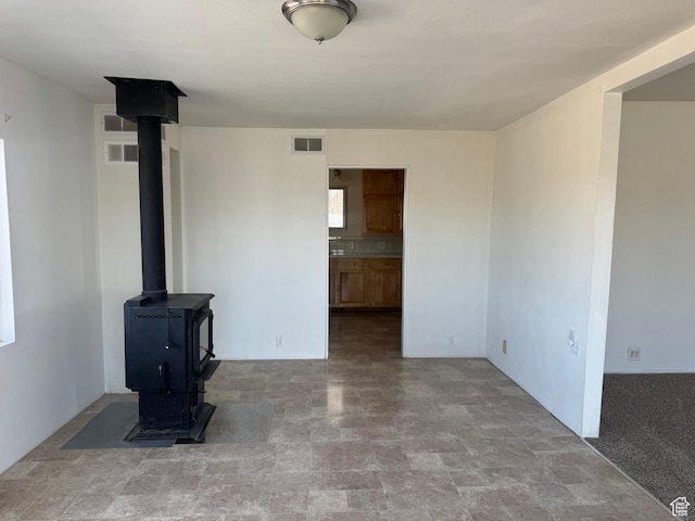 unfurnished living room with a wood stove, visible vents, and stone finish floor