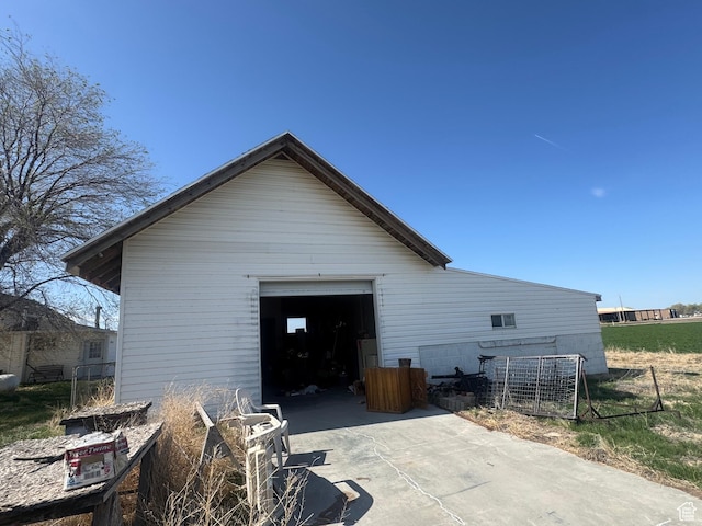 view of property exterior featuring fence, an outdoor structure, driveway, and a detached garage