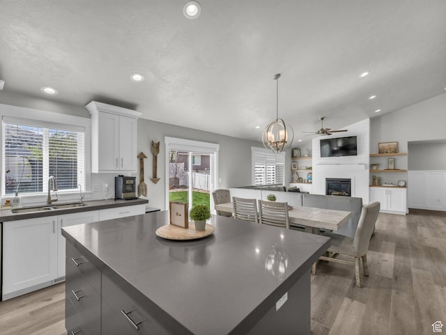 13952 S Indian Ln E, Herriman, UT 84096 - kitchen with a large fireplace, dark countertops, a sink, white cabinets, and recessed lighting