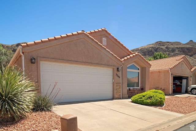 2369 S 780 W, Hurricane, UT 84737 - view of front of home with stucco siding, a garage, a tile roof, driveway, and a mountain view