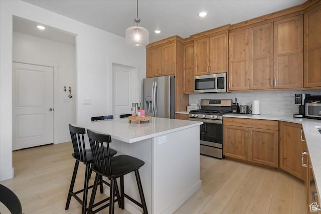 574 W 500 N, Smithfield, UT 84335 - kitchen featuring a kitchen breakfast bar, brown cabinets, decorative backsplash, appliances with stainless steel finishes, and light wood-type flooring
