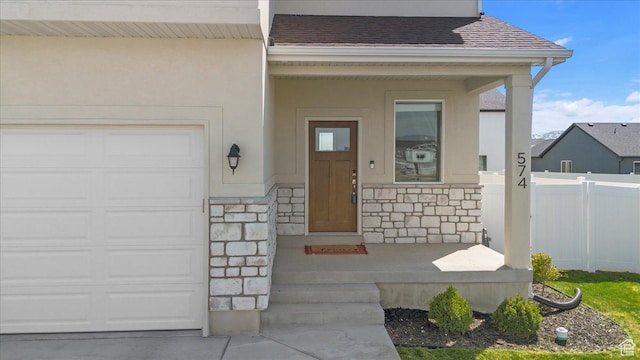 574 W 500 N, Smithfield, UT 84335 - view of exterior entry featuring stone siding, stucco siding, roof with shingles, an attached garage, and fence