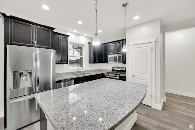5103 W S Jordan Pkwy, South Jordan, UT 84009 - kitchen featuring light stone counters, appliances with stainless steel finishes, a kitchen island, a sink, and light wood-type flooring