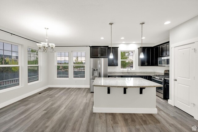 5103 W S Jordan Pkwy, South Jordan, UT 84009 - kitchen with light wood-style flooring, a sink, appliances with stainless steel finishes, a kitchen island, and light stone countertops