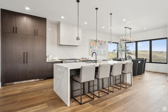 4014 Aspen Camp Loop, Park City, UT 84098 - kitchen with a sink, a center island with sink, a breakfast bar area, wall chimney range hood, and light countertops