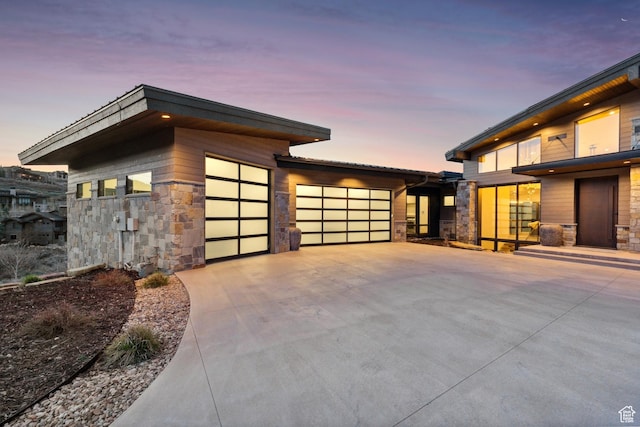 4014 Aspen Camp Loop, Park City, UT 84098 - property exterior at dusk with driveway, stone siding, and an attached garage