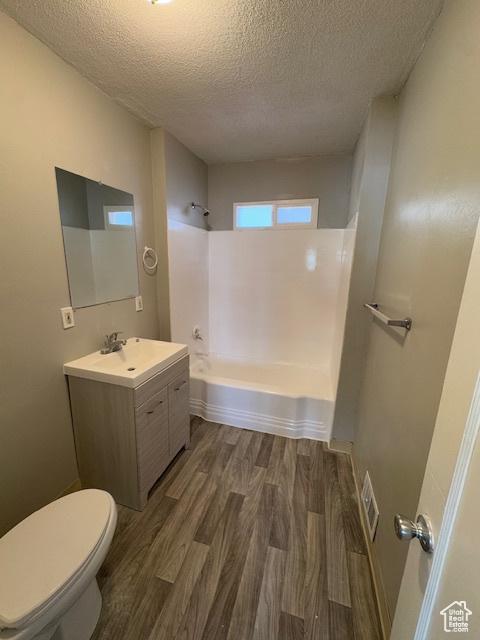 983 29th St, Ogden, UT 84403 - bathroom featuring wood finished floors, a textured ceiling, vanity, and shower / washtub combination