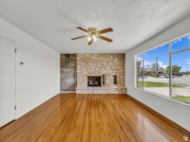 8323 S Adams St, Midvale, UT 84047 - unfurnished living room with wood finished floors, a stone fireplace, ceiling fan, and baseboards