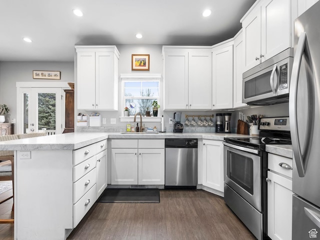 kitchen featuring a peninsula, a sink, appliances with stainless steel finishes, and a healthy amount of sunlight