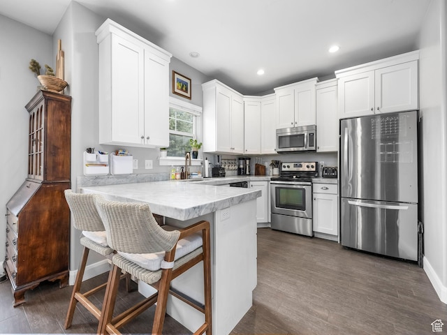 kitchen with white cabinets, appliances with stainless steel finishes, light countertops, recessed lighting, and a peninsula