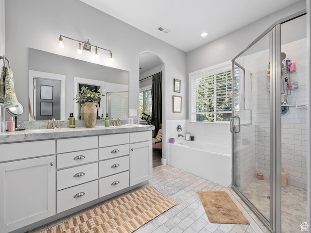 bathroom featuring a bath, a stall shower, double vanity, and a sink
