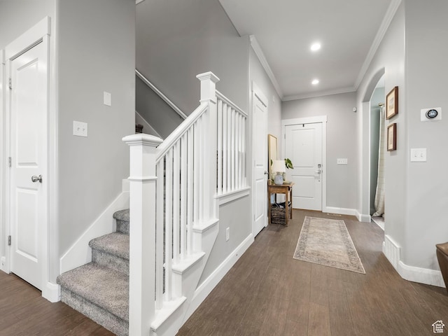 foyer entrance featuring crown molding, stairs, baseboards, arched walkways, and wood finished floors