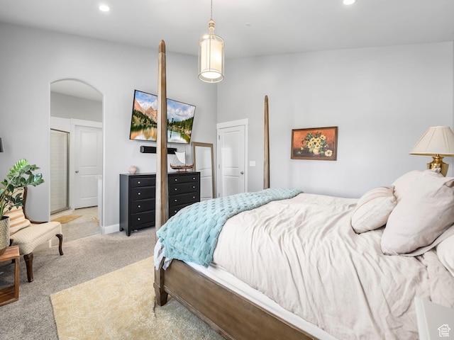 bedroom with recessed lighting, arched walkways, and light carpet