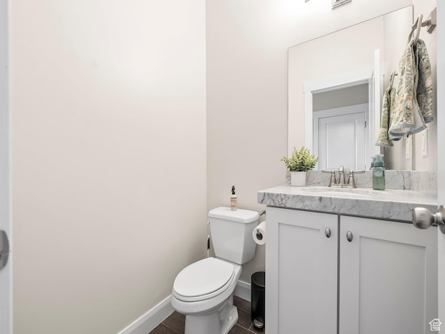 bathroom featuring toilet, vanity, and baseboards