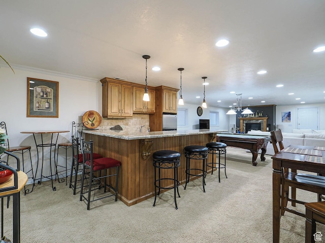 kitchen featuring recessed lighting, light stone countertops, a breakfast bar area, a peninsula, and light carpet