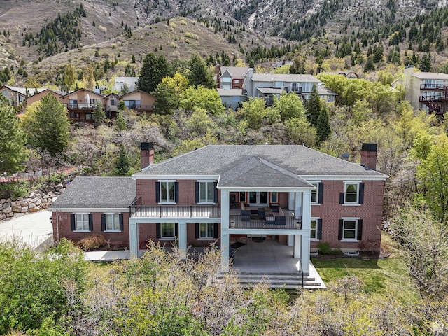 rear view of house with a deck with mountain view, a chimney, and brick siding