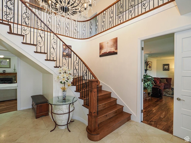 stairs featuring a high ceiling, tile patterned flooring, an inviting chandelier, and baseboards