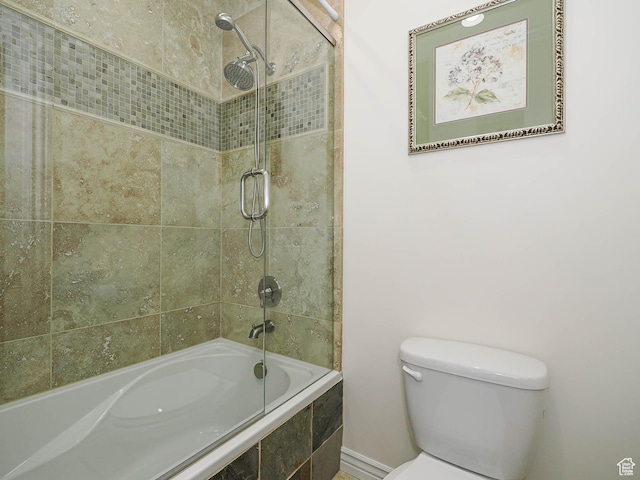bathroom featuring baseboards, toilet, and tiled shower / bath