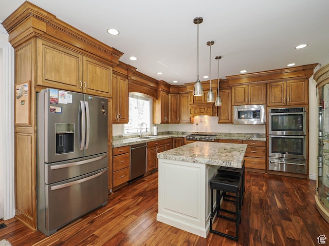 kitchen featuring brown cabinets, a warming drawer, hanging light fixtures, appliances with stainless steel finishes, and dark wood finished floors