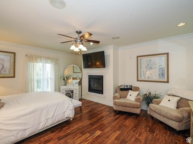 bedroom with a glass covered fireplace, ceiling fan, crown molding, and dark wood finished floors