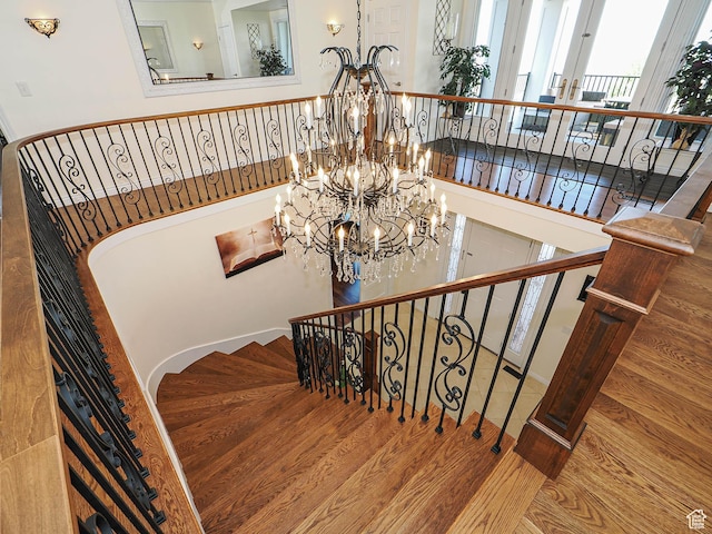 staircase with wood finished floors and a chandelier