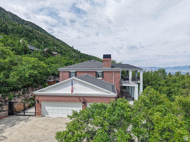 4545 S Abinadi Rd, Salt Lake City, UT 84124 - view of side of property with a balcony, brick siding, a chimney, a mountain view, and concrete driveway