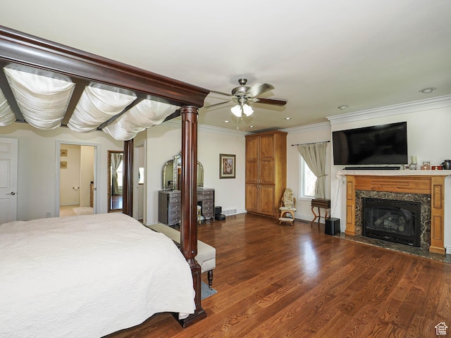 bedroom with a fireplace, visible vents, ornamental molding, and dark wood finished floors