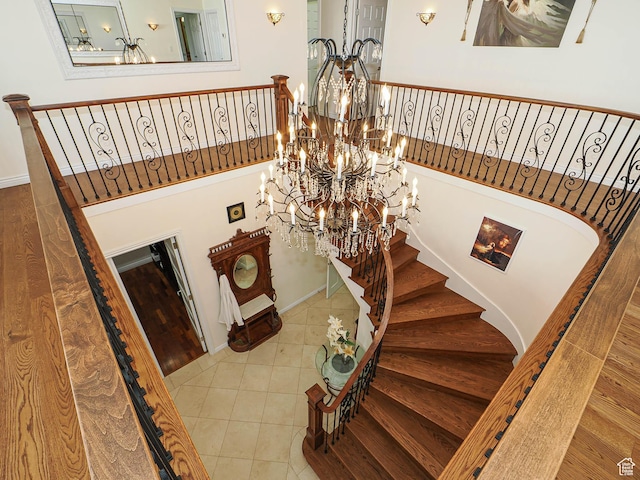 stairs with a notable chandelier, tile patterned floors, and baseboards