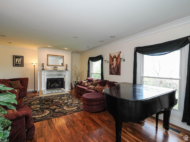 living room with crown molding, visible vents, wood finished floors, and a fireplace with raised hearth