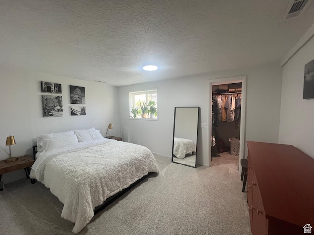 240 S 100 E, Logan, UT 84321 - bedroom with light colored carpet, a walk in closet, a textured ceiling, visible vents, and a closet