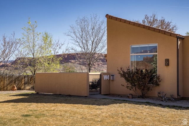 3686 S Spanish Valley Dr Unit W-4, Moab, UT 84532 - view of side of home with a gate, fence, a mountain view, a yard, and stucco siding