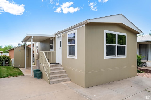 view of front of property featuring a patio, a shed, and an outbuilding