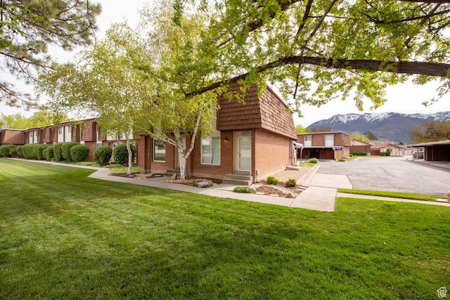 3937 S Lamplighter Way Unit 23, Riverdale, UT 84405 - back of house with entry steps, a lawn, a mountain view, mansard roof, and brick siding